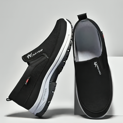 Et par sorte ortopædiske slip-on-sko til herrer, hvor sålen og inderforet ses ovenfra