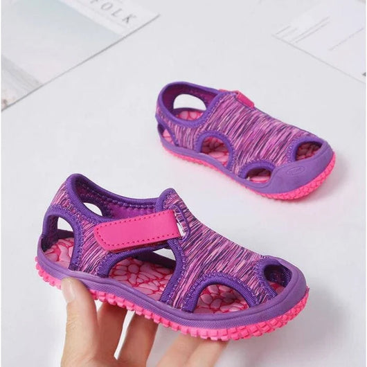 Lilla børnesandaler med velcro, holdt i hånden