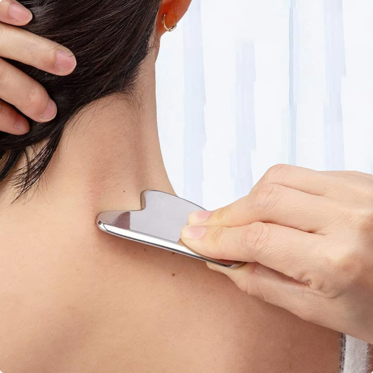 Kvinde bruger en Gua Sha-massageskraber på nakken og skulderen