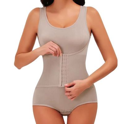 Kvinde knapper korsetdelen på en beige figurformende body, nærbillede af taljen