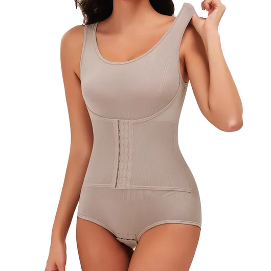 En kvinde justerer skulderbåndet på en beige figurformende body med korset