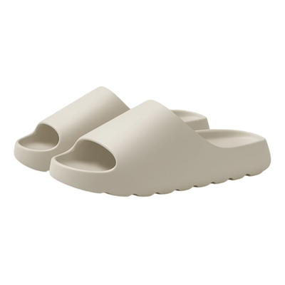 Slip-on-tøfler i beige EVA-materiale med tyk, blød sål og bølgemønstret underside på hvid baggrund
